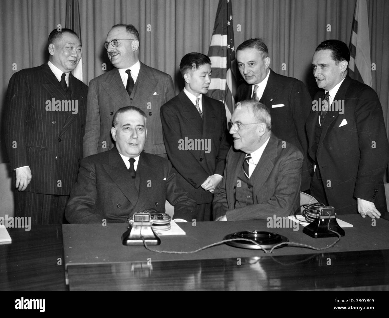 Il Premier francese René Mayer (seduto a sinistra) e il Segretario di Stato John Foster Dulles (seduto) iniziarono consultazioni dettagliate presso il Dipartimento di Stato, aiutati dai loro migliori consiglieri. Da sinistra a destra, retroguardia: Nony Kimmy, ambasciatore cambogiano; Jean LeTourneau, ministro degli Stati associati dell'Indocina; Tran Van Kha, ambasciatore del Vietnam; Georges Bidault, ministro degli Esteri francese; e Maurice Bourges-Maunery, ministro delle Finanze francese. 26 marzo 1953 Foto Stock