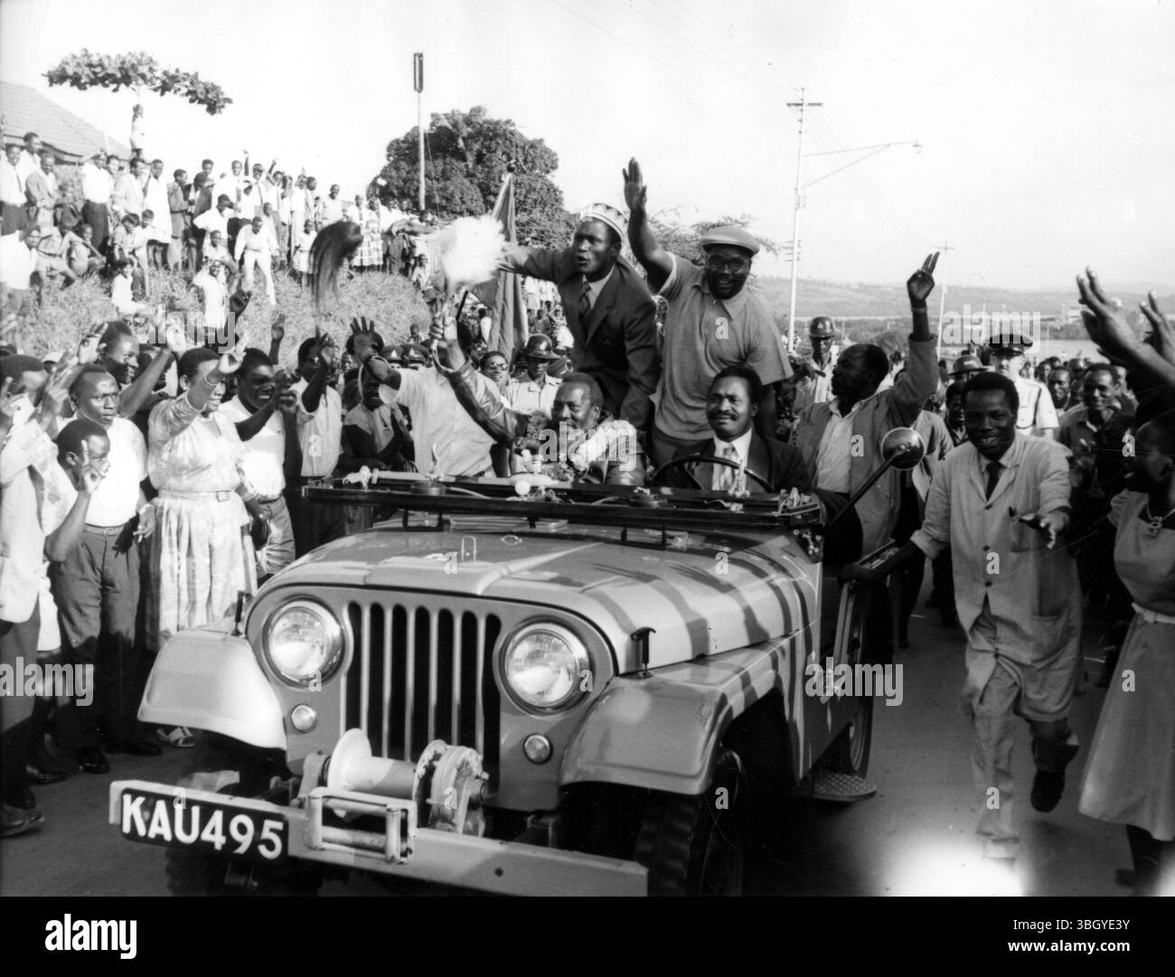 I seguaci dell'ex leader Mau Mau, "Burning Spear" Jomo Kenyatta (garlanato lasciato in auto) si rallegrarono quando guidò per le strade di Mobasa. CAN Natter era in visita a Mobasa per la prima volta in 9 anni, e si rivolse a una vasta folla, disse: "Il Kenya è nostro, non possiamo venderne nemmeno un centimetro. Da 40 anni combatto per la libertà del Kenya e sono sorpreso che ci siano persone che chiedono l'autonomia costiera. Siamo contrari a questa sporcizia.” Stava attaccando le richieste di autonomia della striscia costiera, che è affittata dalla Gran Bretagna dal sultano di Zanzibar. 4 settembre 1961 Foto Stock