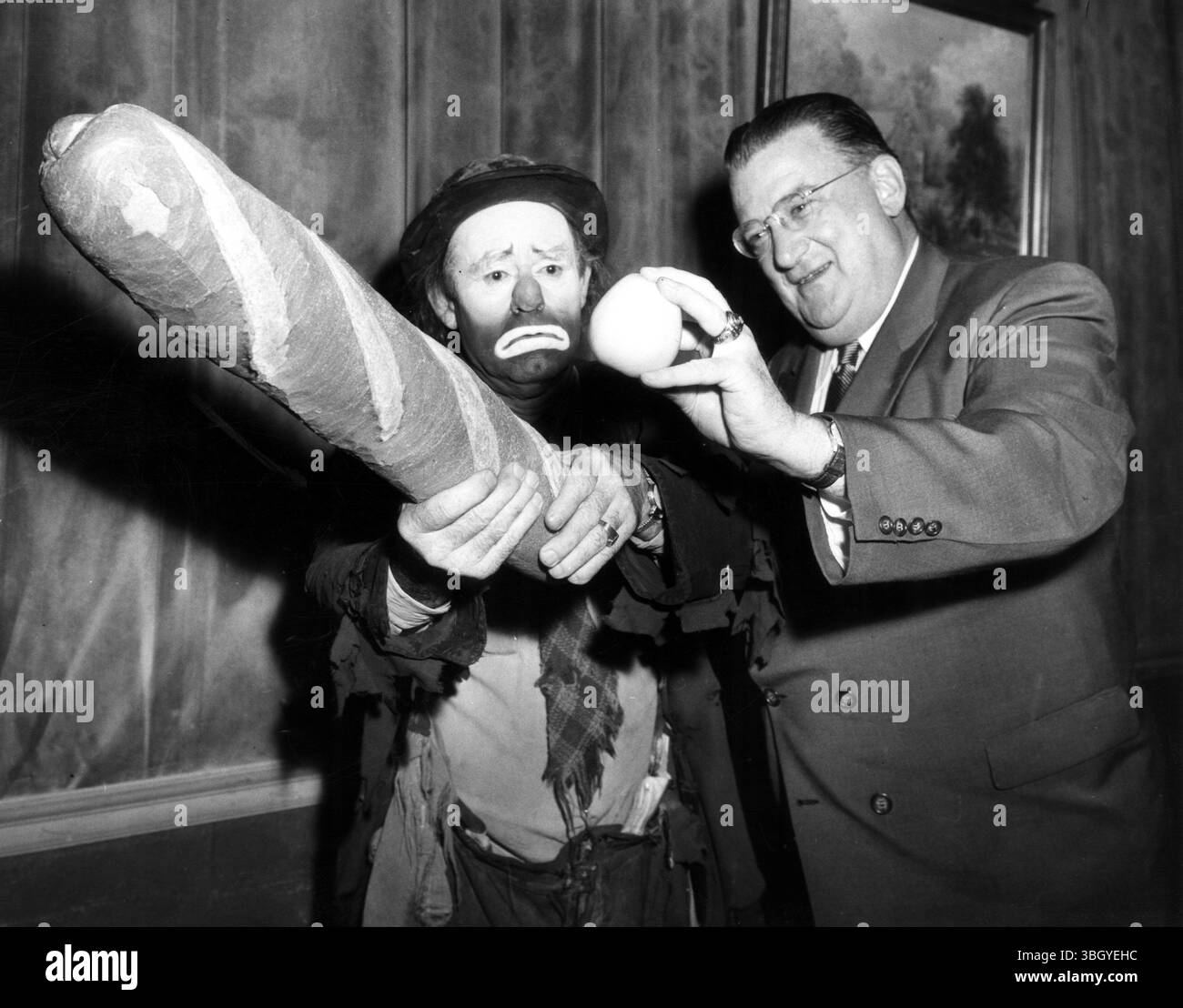 Clown Emmett Kelly (a sinistra), ex Ringling Bros, clown del circo, dondola il pipistrello (enorme pane italiano) e una palla (una mela) tenuta dal proprietario dei Brooklyn Dodgers Walter o'Malley, mentre si esibiscono in una cena di fotografi della stampa al Leones. Walter o'Malley ha ingaggiato e famoso clown per fare il suo (circo bum) atto questa stagione per 'realizzare la tensione all'Ebbets Field.) Kelly, 58 anni, si diverte per le partite casalinghe dei Dodger e tra gli inning a Brooklyn e Jersey City. 28 gennaio 1956 Foto Stock