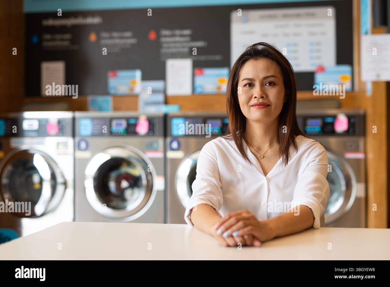 Ritratto di una bella donna asiatica seduta in un negozio di lavanderia Foto Stock