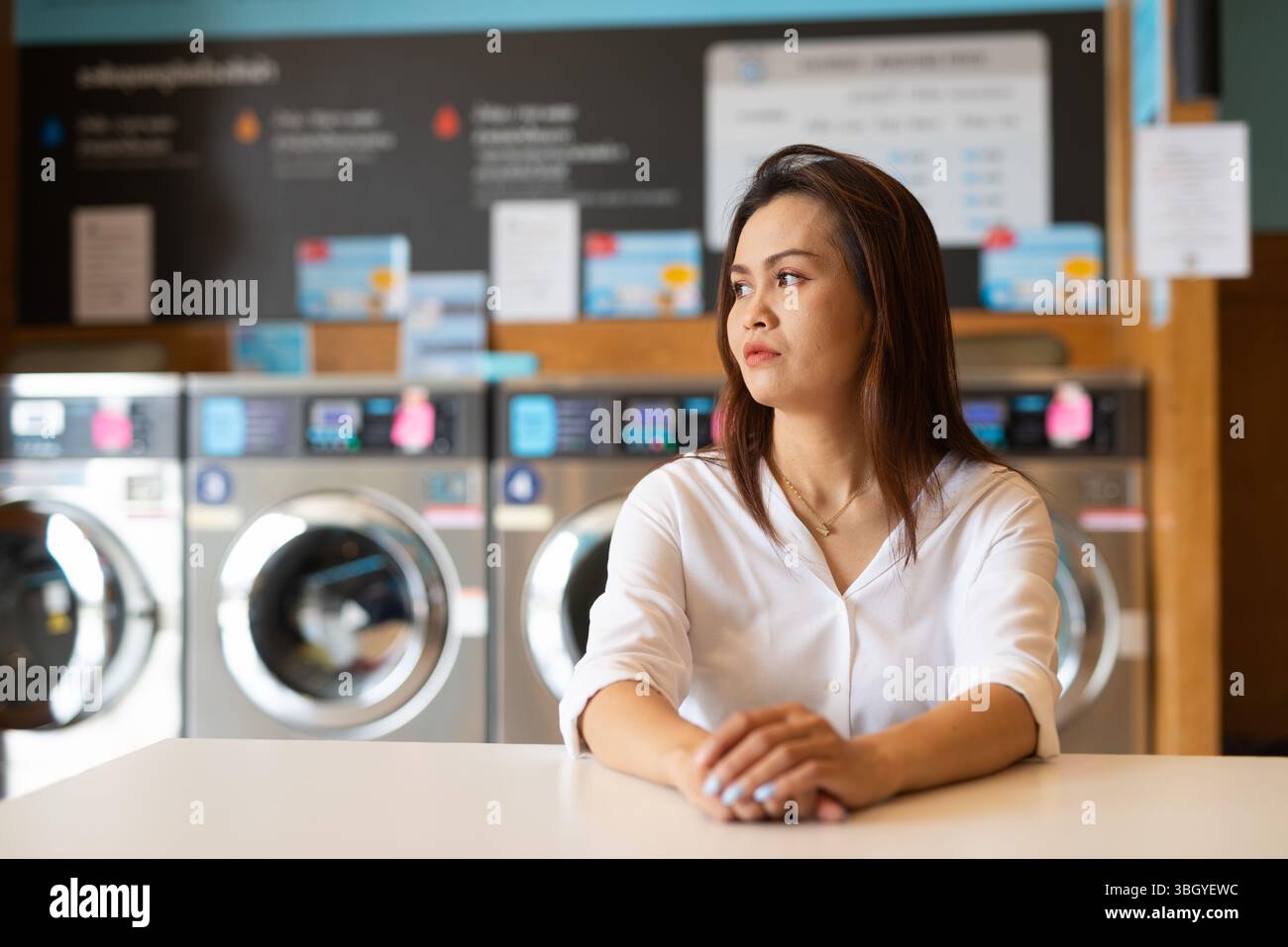 Ritratto di una bella donna asiatica seduta in un negozio di lavanderia Foto Stock