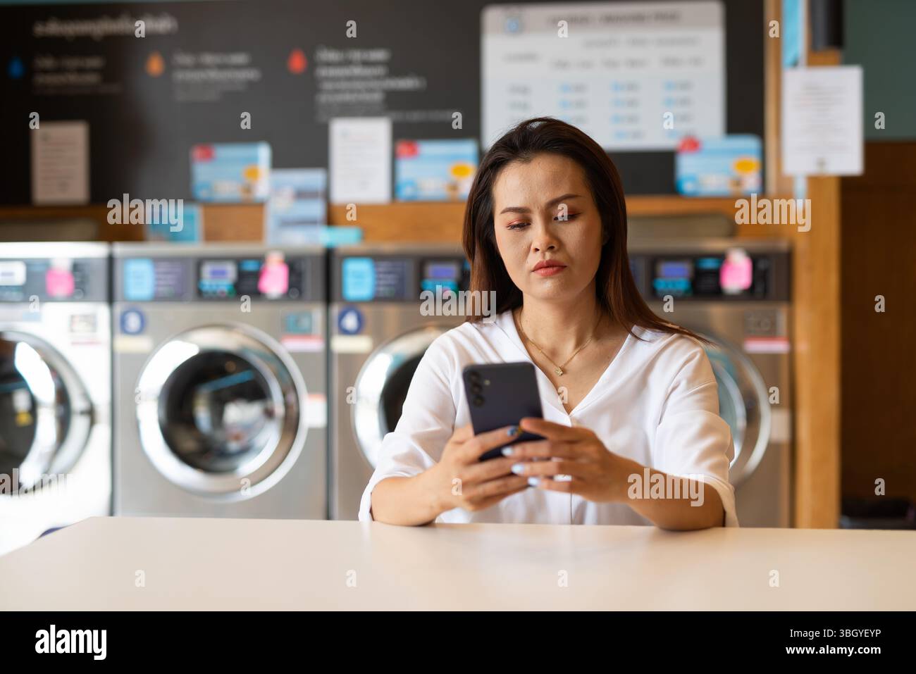 Ritratto di una bella donna asiatica seduta in un negozio di lavanderia Foto Stock
