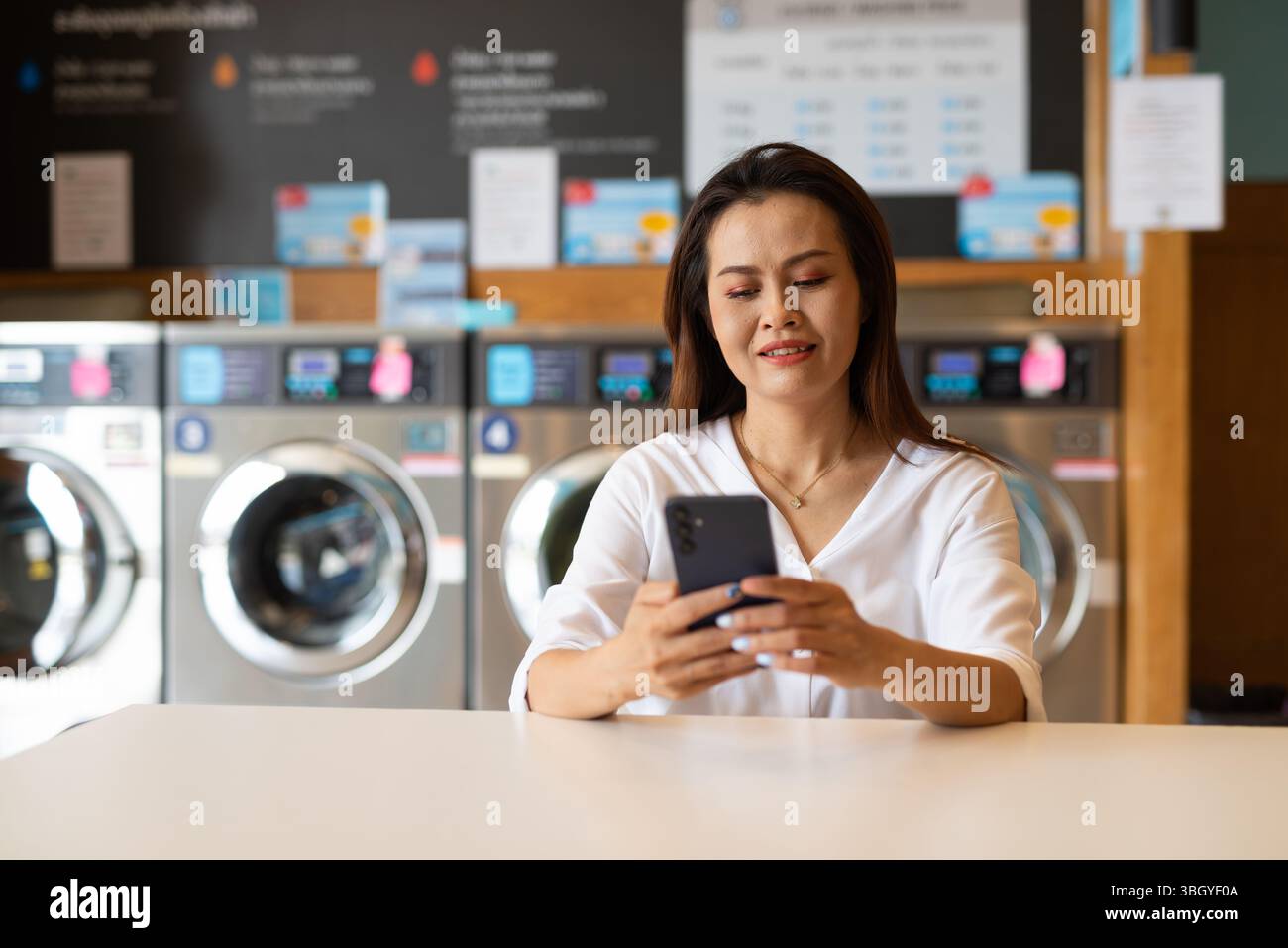 Ritratto di una bella donna asiatica seduta in un negozio di lavanderia Foto Stock