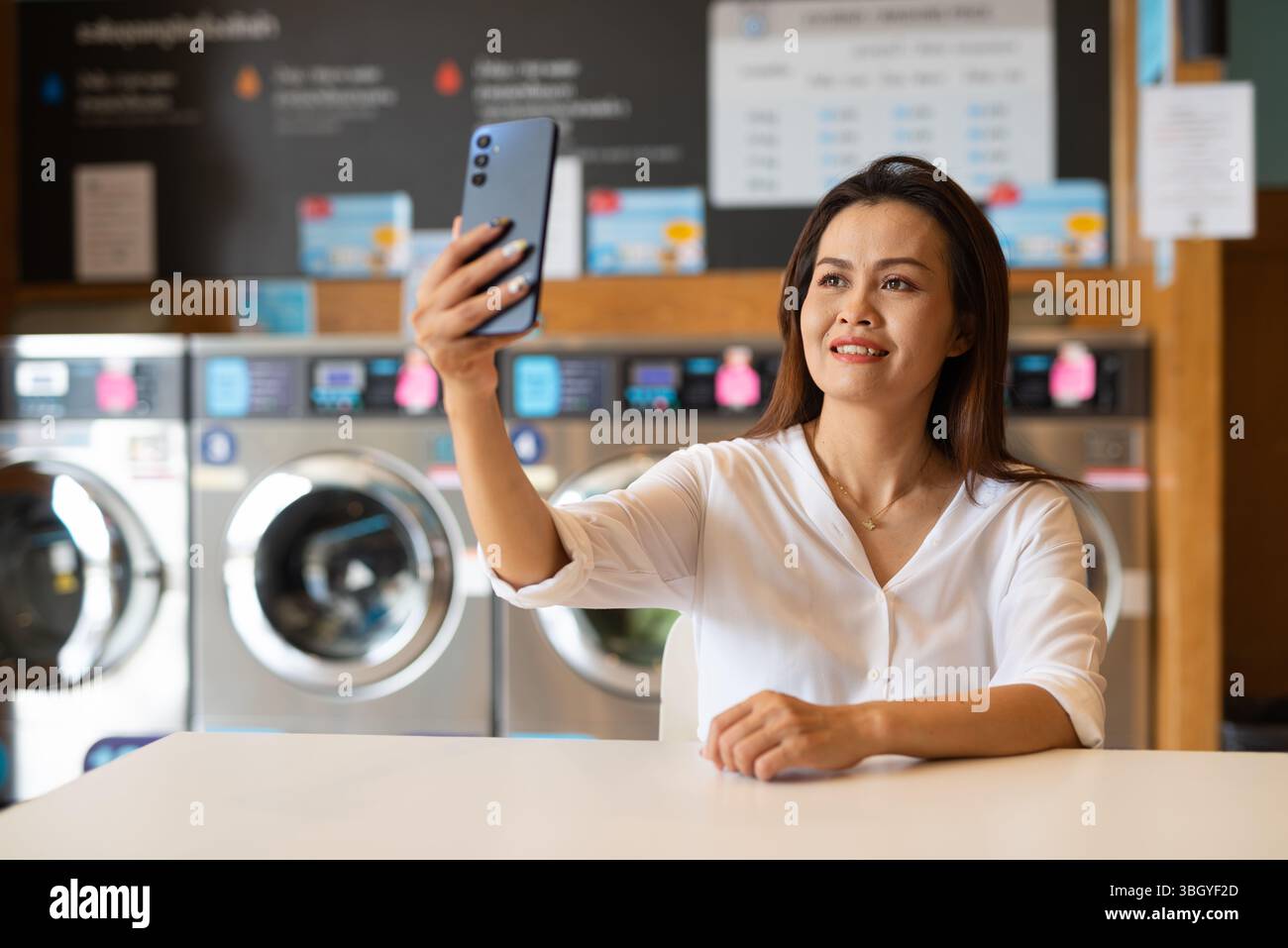 Ritratto di una bella donna asiatica seduta in un negozio di lavanderia Foto Stock