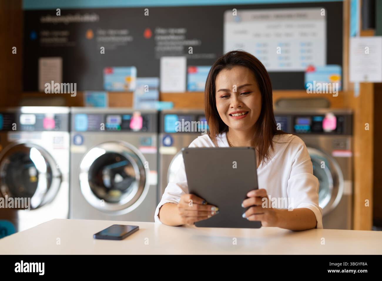Ritratto di una bella donna asiatica seduta in un negozio di lavanderia Foto Stock