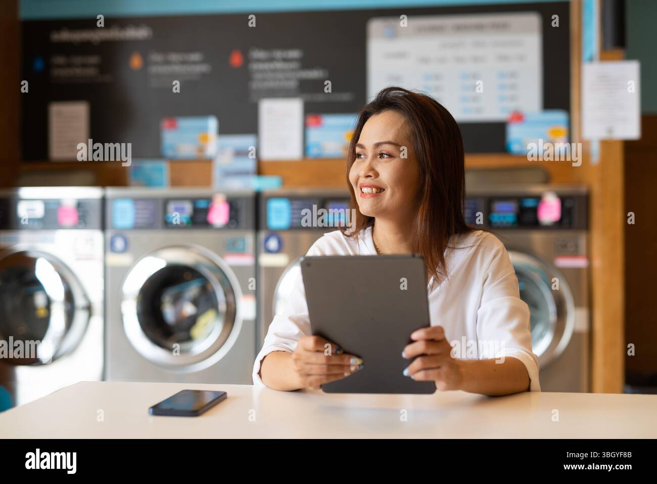 Ritratto di una bella donna asiatica seduta in un negozio di lavanderia Foto Stock