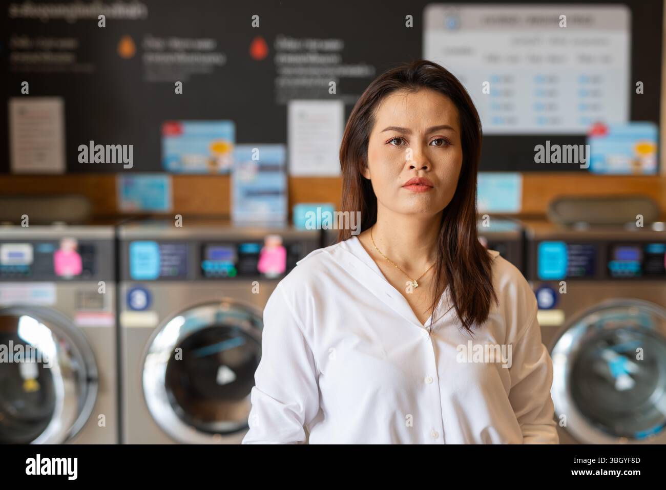 Ritratto di una bella donna asiatica seduta in un negozio di lavanderia Foto Stock