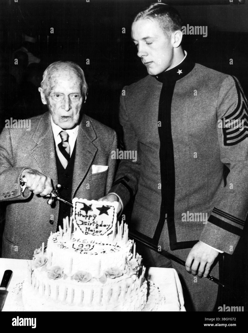 Come cadetto Pete Dawkins presta assistenza, il maggiore generale Henry Clay Hodges, il più anziano laureato vivente di West Point, si prepara a tagliare la torta di compleanno in una cerimonia che è stato ospite d'onore. 20 aprile 1959 Foto Stock