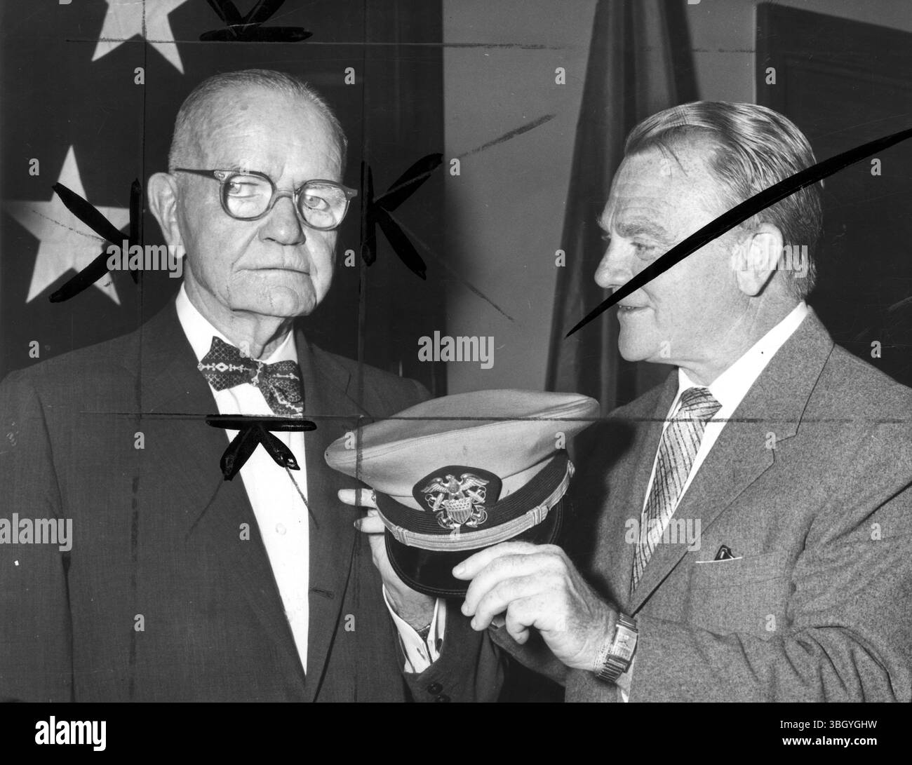 L'attore James Cagney (a destra) e l'ammiraglio della flotta in pensione William F Halsey guardano il cappello di un ufficiale dopo che è stato annunciato che Cagney ha fatto un lungometraggio basato sulla vita di Halsey. 11 giugno 1957 Foto Stock