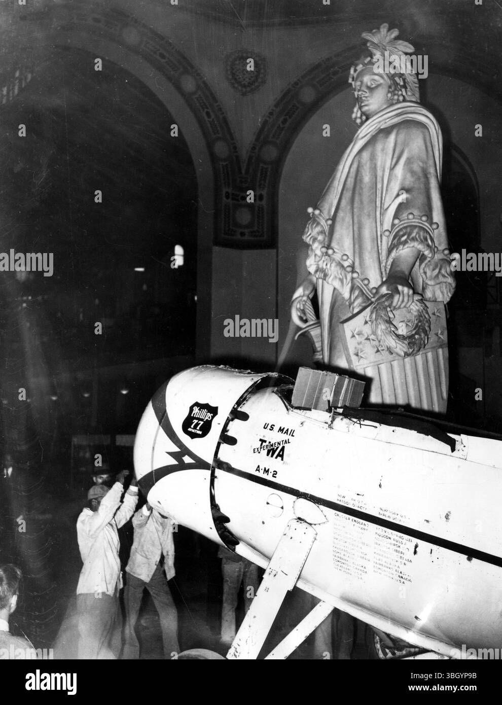 Operai che trasportano il famoso aereo ' Winnie Mae' volato da Wiley Post in molti voli da record, nel suo luogo di riposo presso lo Smithsonian Institute dove sarà esposto al pubblico. La statua è " libertà " , un duplicato di quello che adorna la cupola del Campidoglio degli Stati Uniti Foto Stock