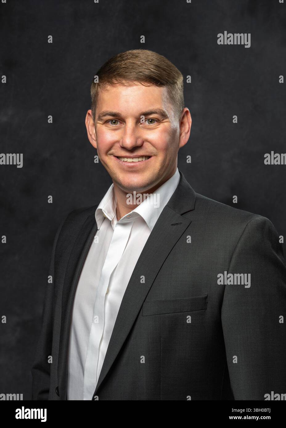 Ritratto in studio di un giovane allegro che indossa una camicia bianca e una giacca classica. Sfondo scuro. Concetto di eleganza moderna, professionalità e Foto Stock