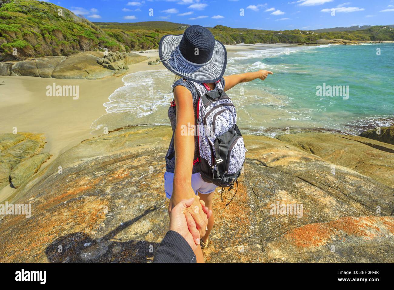 Follow me POV. Donna in hat tenendo la mano del suo amico a cascata Beach in Danimarca, Western Australia. Saccopelisti a William Bay NP un popolare Austra Foto Stock