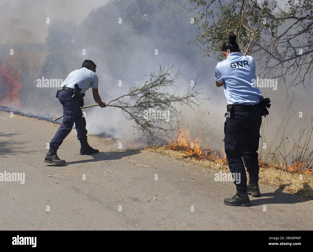 Incendi boschivi ad Armacao de Pera, Algarve - Portogallo. Coraggiosi agenti di polizia della GNR cercano di spegnere le fiamme finché non intervengono i vigili del fuoco Foto Stock
