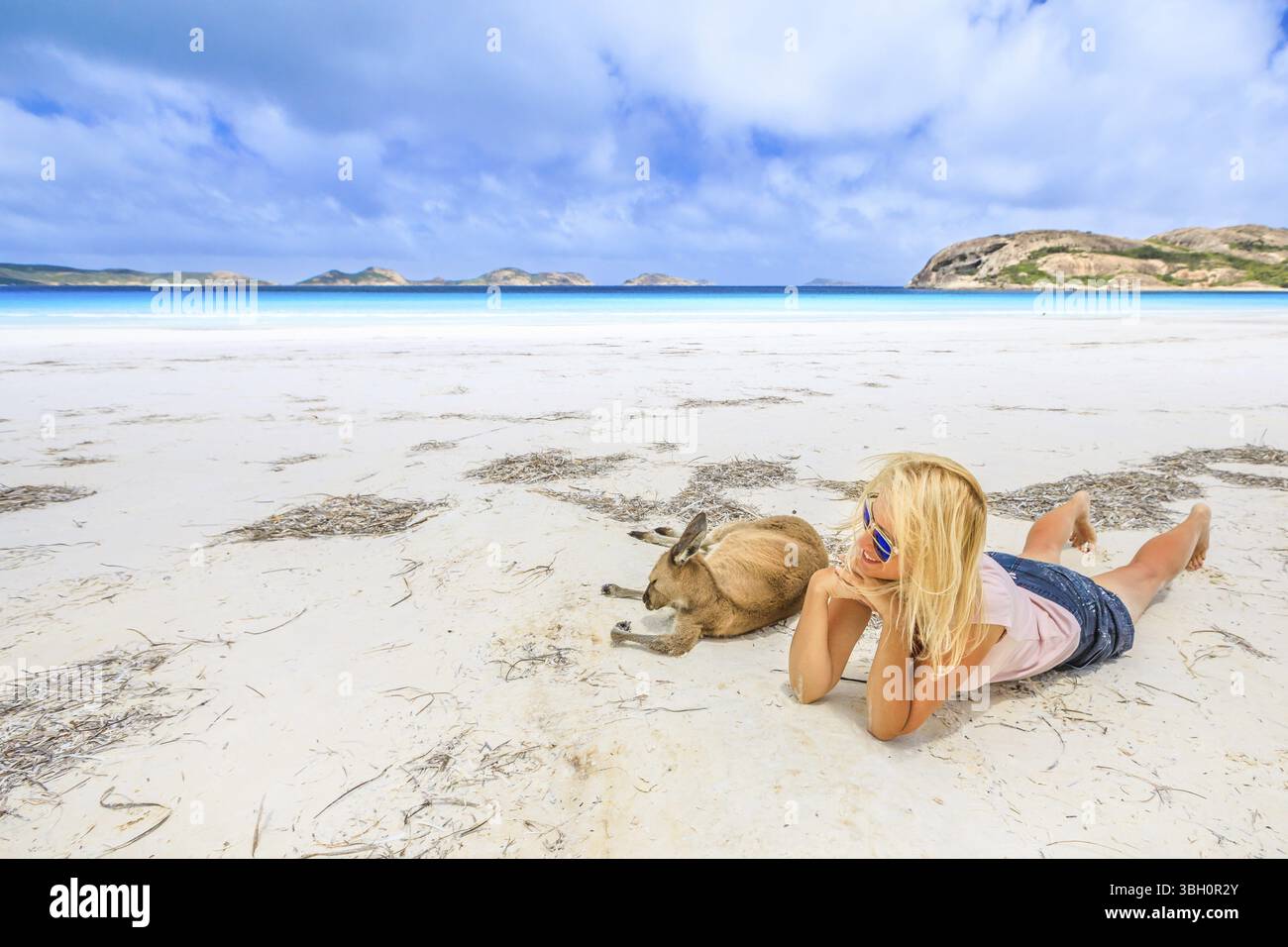 Donna felice che giace sulla sabbia bianca incontaminata di Lucky Bay vicino a Kangaroo. Cape le Grand National Park, Esperance, Australia Occidentale. Le donne turistiche amano Foto Stock