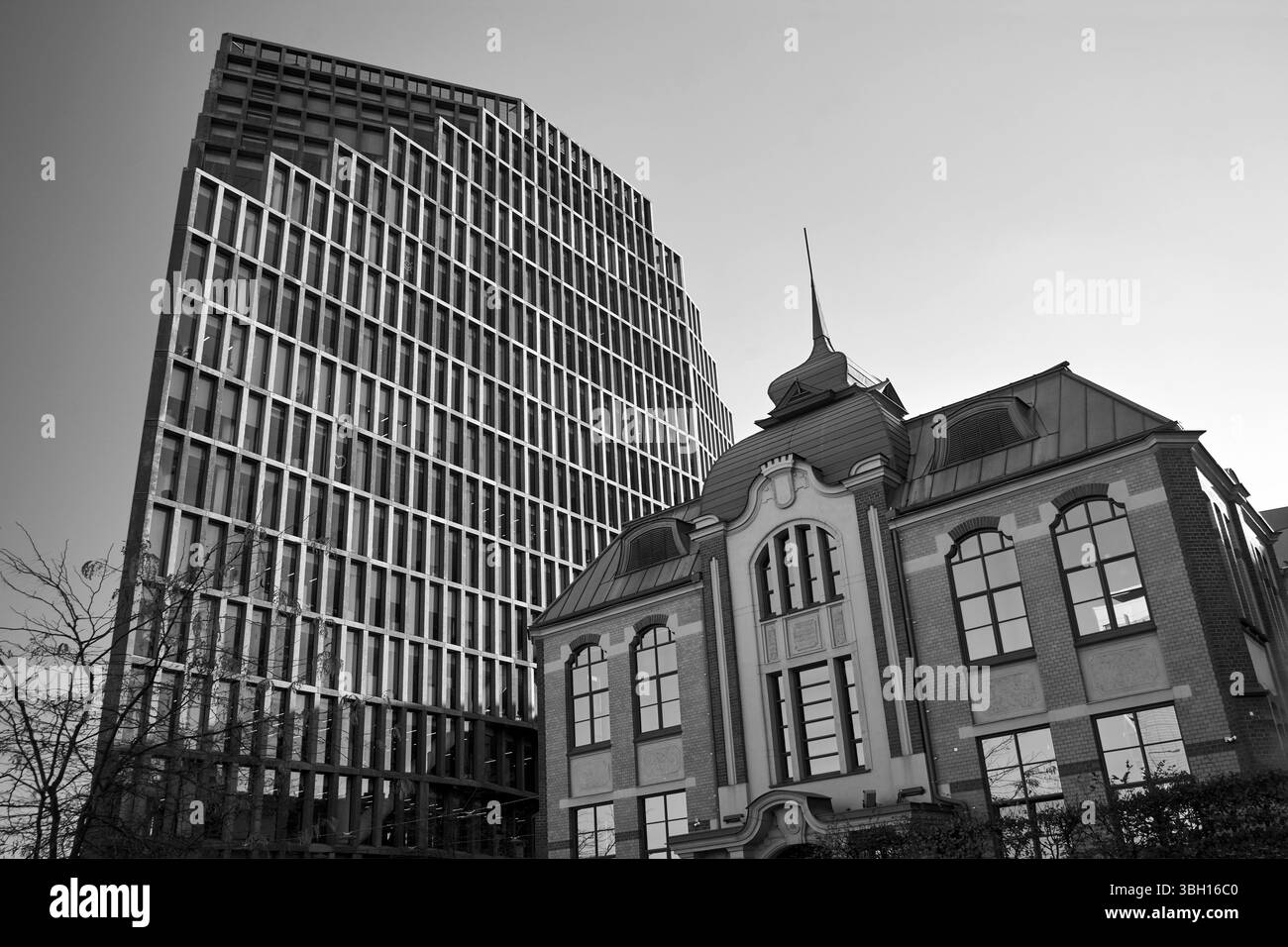 Un edificio storico di un'ex stamperia e un moderno edificio per uffici a più piani nella città di Poznan, Polonia, monocromatico Foto Stock