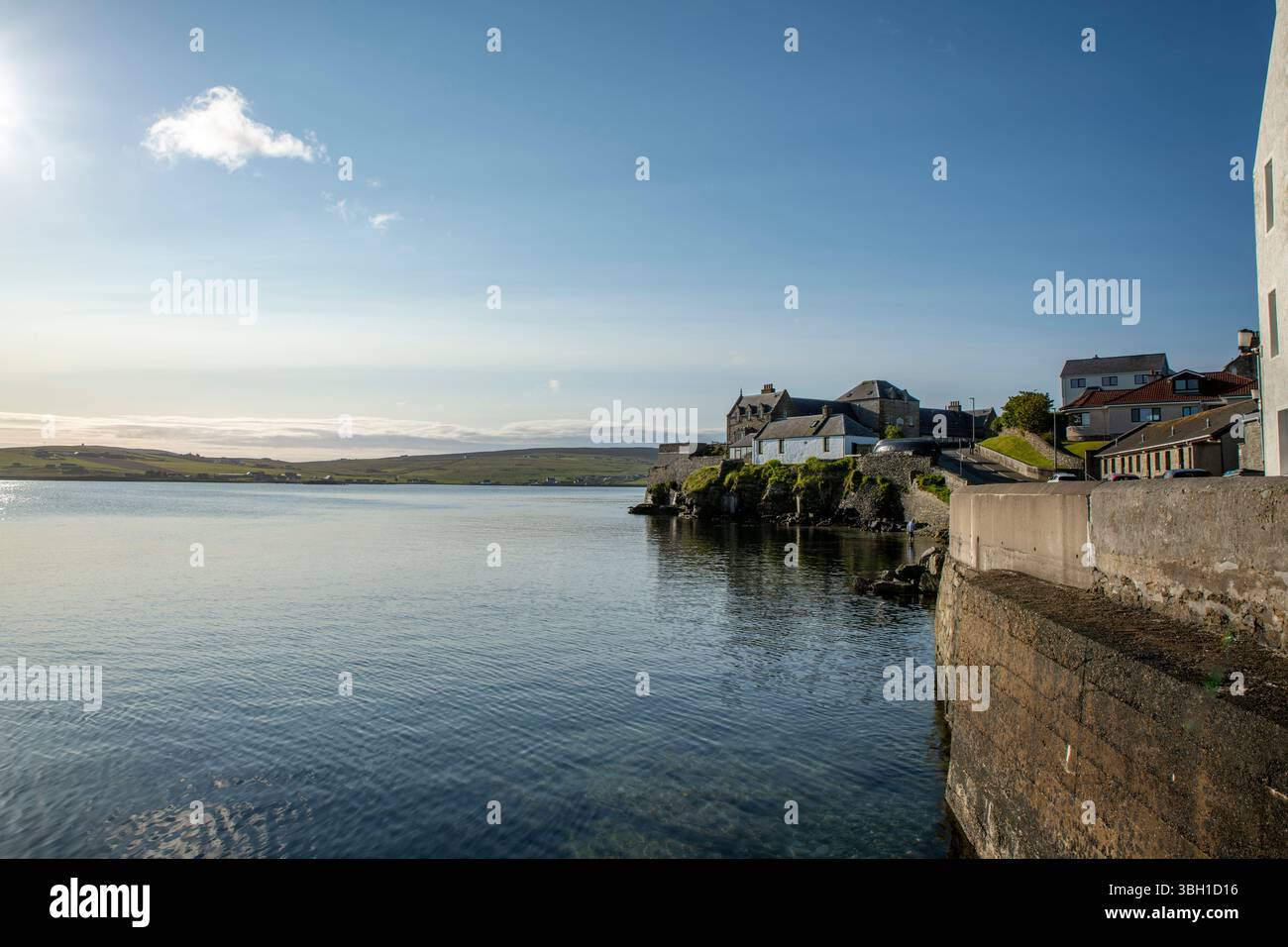 Ingresso sud al porto di Lerwick, Shetland, proprietà costiere in una tranquilla luce estiva con mare tranquillo e cieli blu. Foto Stock