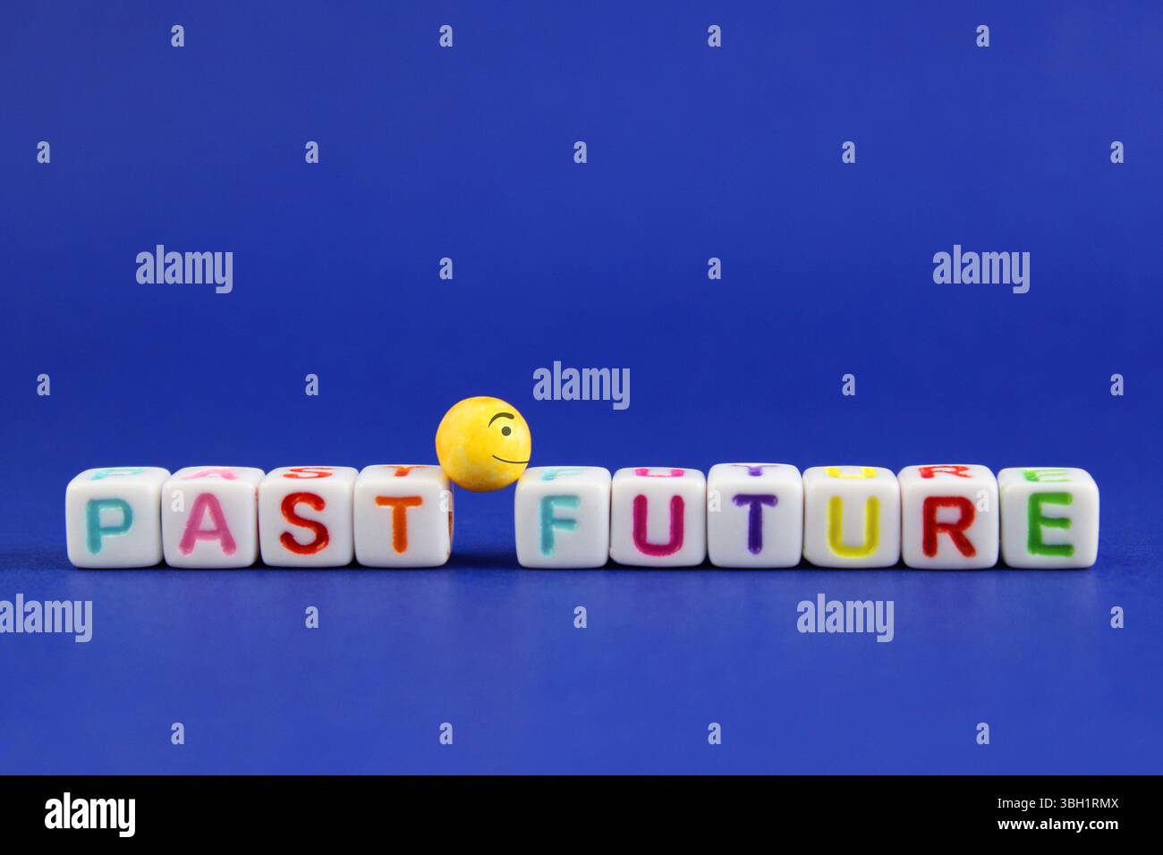Sfera con un volto felice guarda al futuro, lasciando il passato alle spalle, cubi colorati con lettere Foto Stock