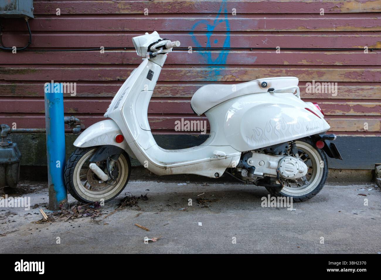 Una Vespa bianca è chiusa con lucchetto a una postazione a Vancouver, British Columbia. Foto Stock