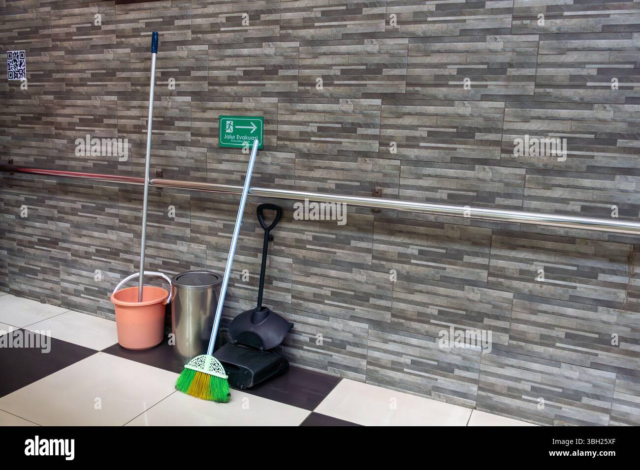 Il cartello verde si trova sul muro accanto a uno spazzolone e a un secchio. Il cartello punta a destra Foto Stock