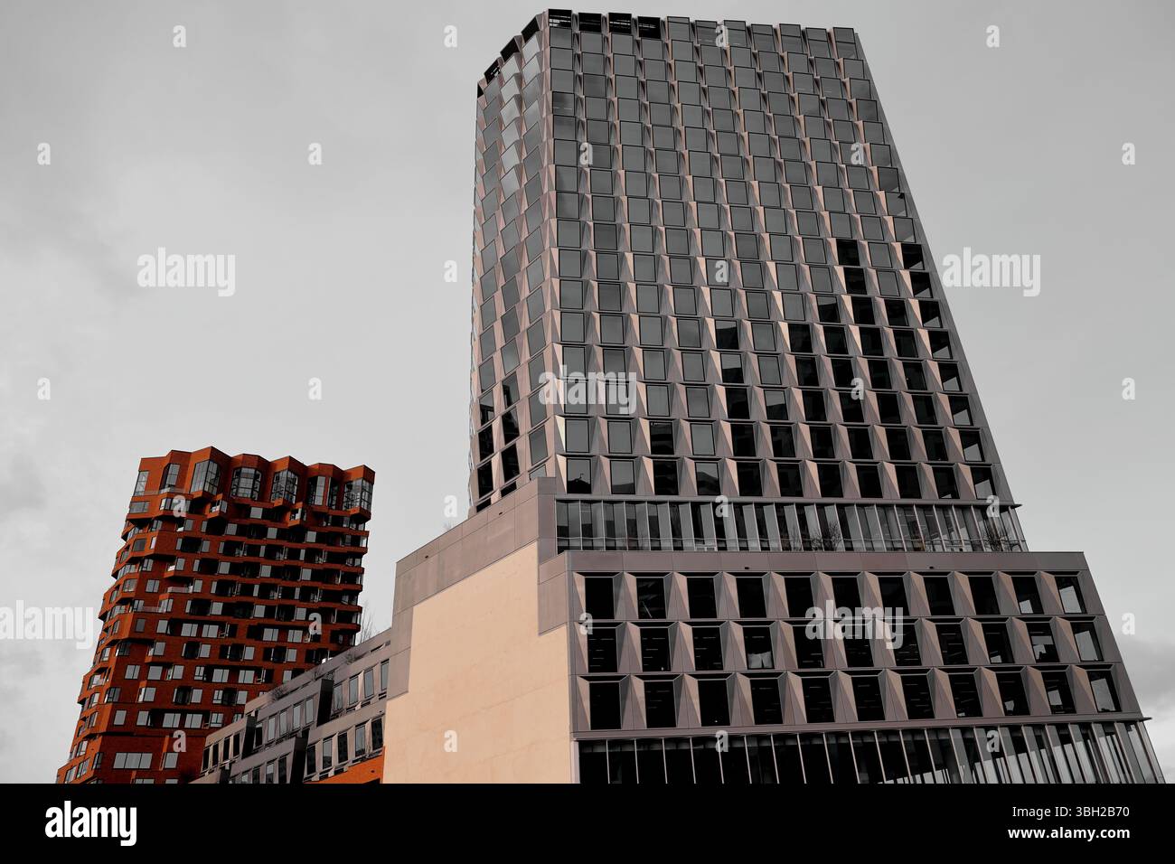 La torre Pulse e la vicina residenza in mattoni rossi portano un contrasto in mattoni di vetro allo skyline di Zuidas di Amsterdam, riflettendo l'architettura contemporanea. Foto Stock