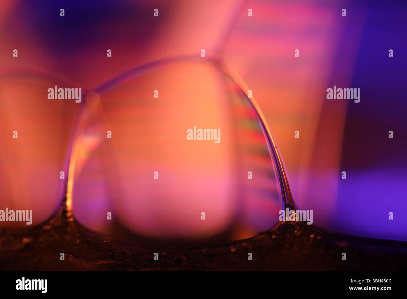 Vetro liquido arancione e viola, fenomenali effetti liquidi, riflessi arancioni brillanti, sfondo chimico Foto Stock