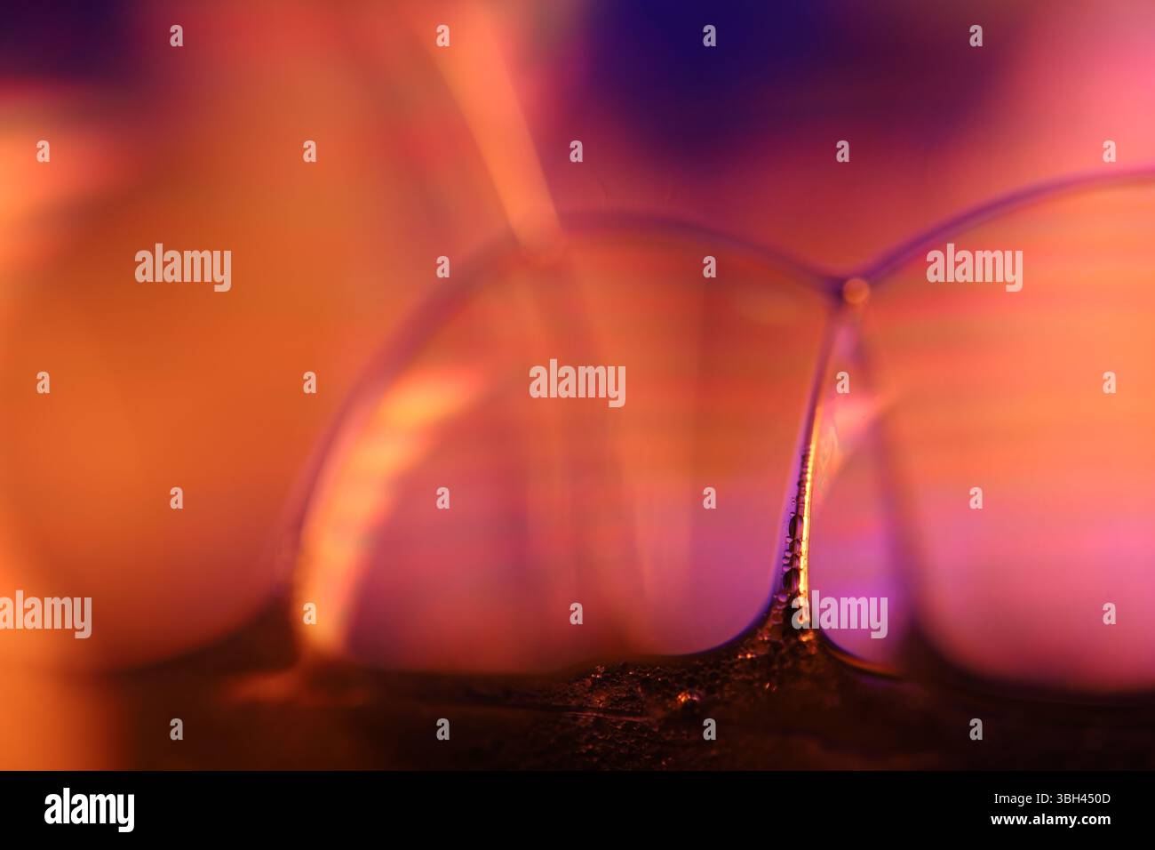 Vetro liquido arancione e viola, fenomenali effetti liquidi, riflessi arancioni brillanti, sfondo chimico Foto Stock