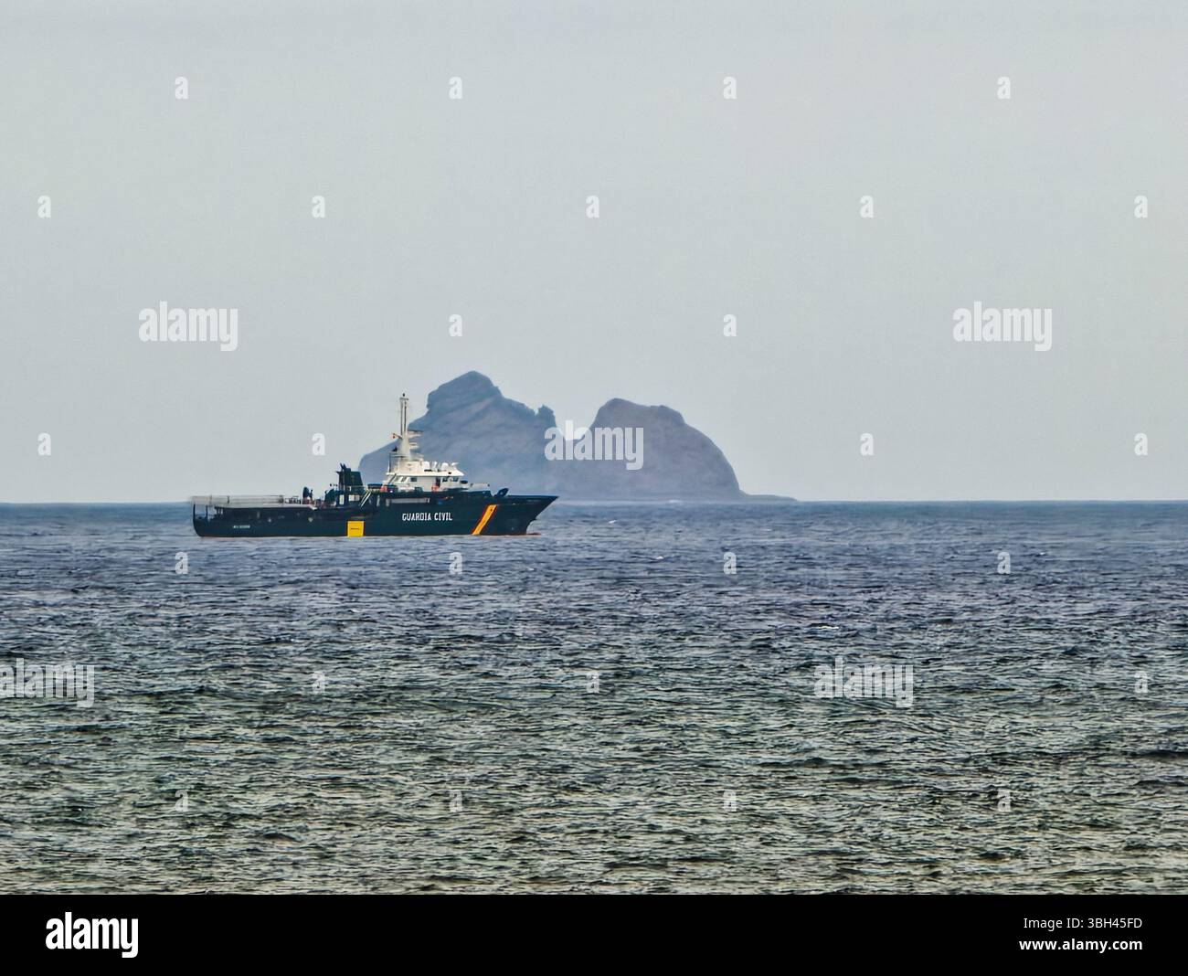 Una motovedetta Guardia Civil opera lungo la costa settentrionale di Lanzarote, supervisionando le acque con l'isola di Alegranza in lontananza. Foto Stock