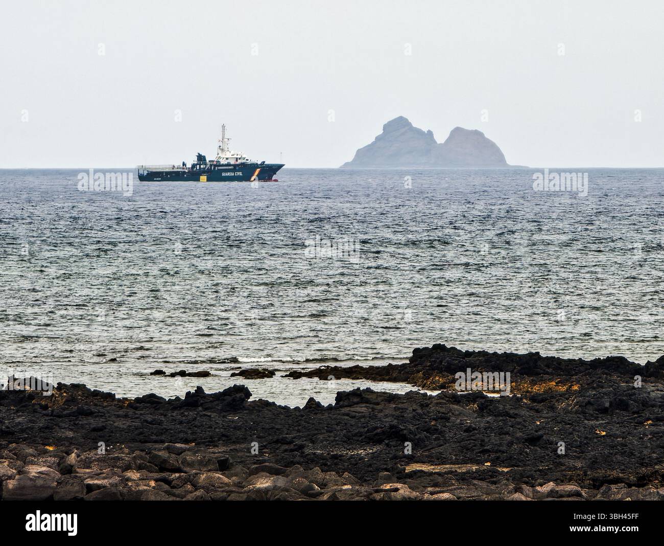 Una motovedetta Guardia Civil opera lungo la costa settentrionale di Lanzarote, supervisionando le acque con l'isola di Alegranza in lontananza. Foto Stock