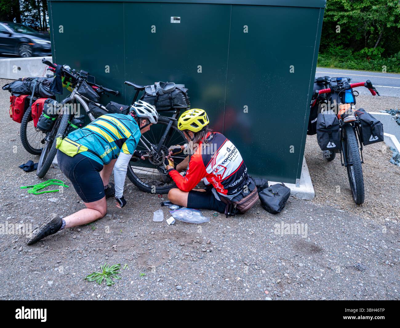 BC00826-00...BRITISH COLUMBIA - Tom aiuta un ciclista a sostituire un raggio rotto con un raggio temporaneo per mantenere la ruota vera. Foto Stock