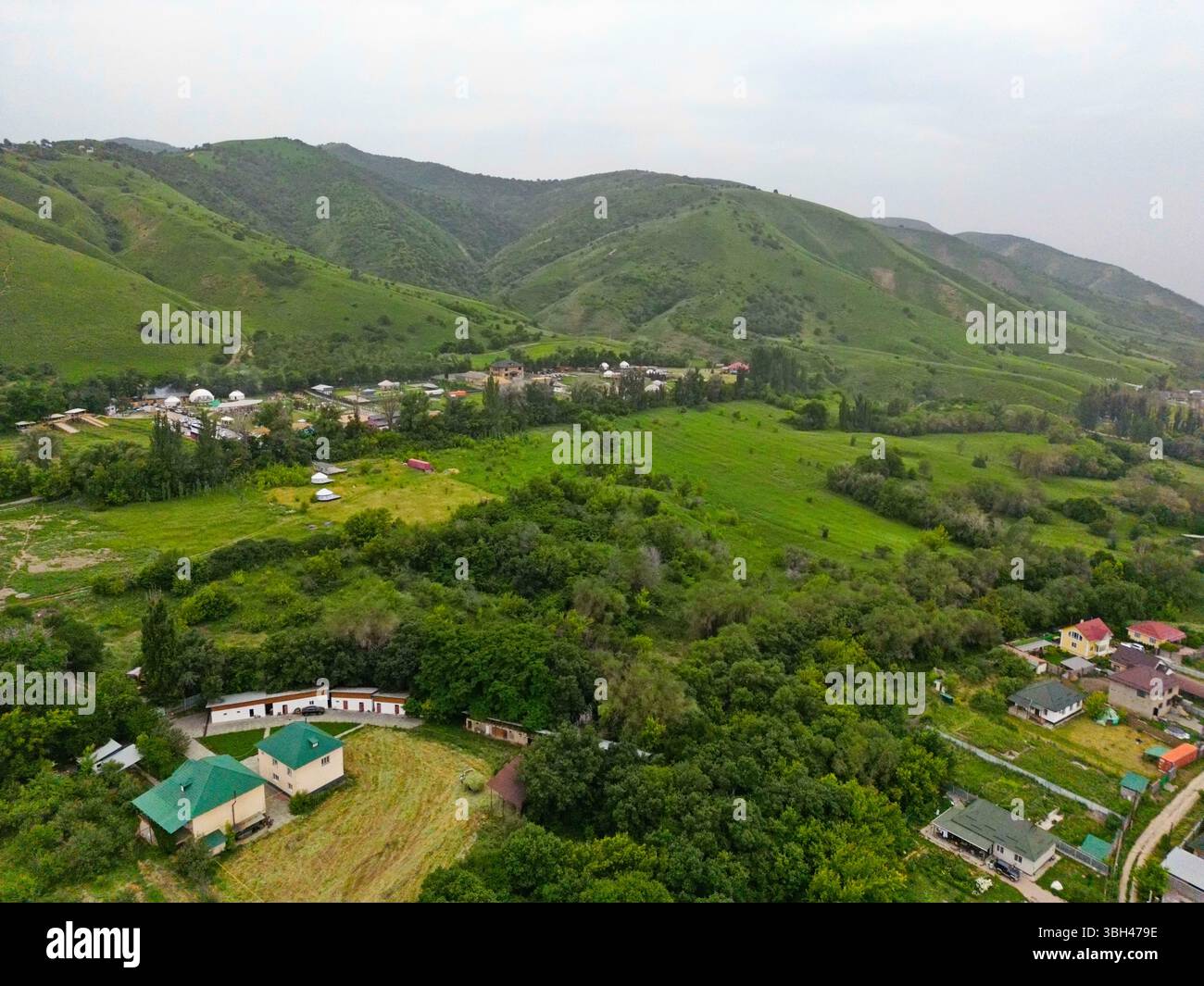 Un villaggio alla periferia della città. Terreno collinare con vegetazione diversa. La vista dal drone. Foto Stock