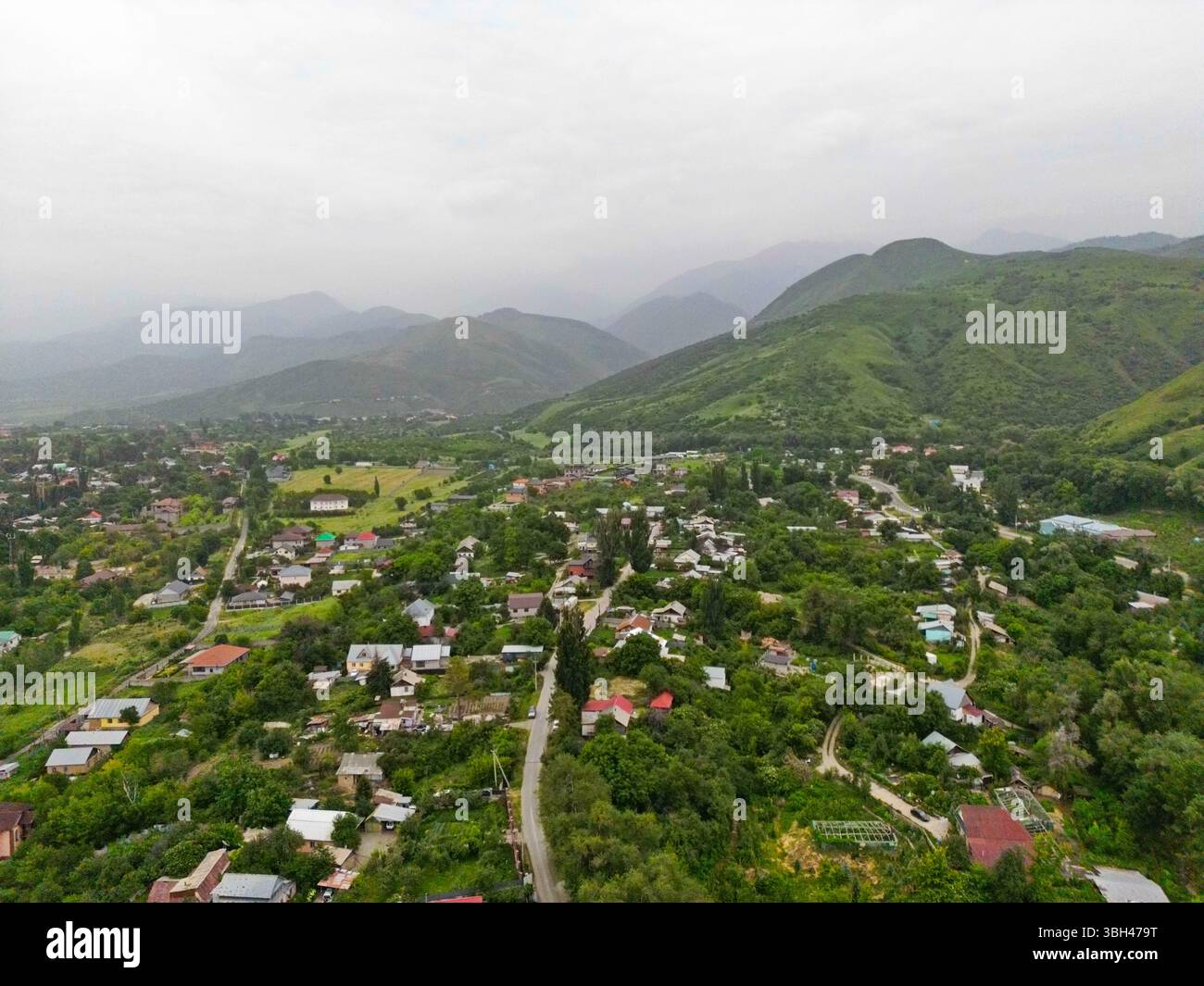 Un villaggio alla periferia della città. Terreno collinare con vegetazione diversa. La vista dal drone. Foto Stock