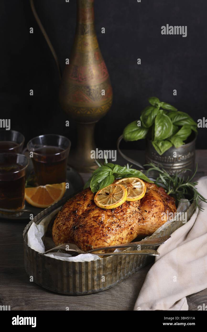 Pollo intero cotto in spezie con crosta fritta croccante e appetitosa in un vassoio, moody scuro Foto Stock