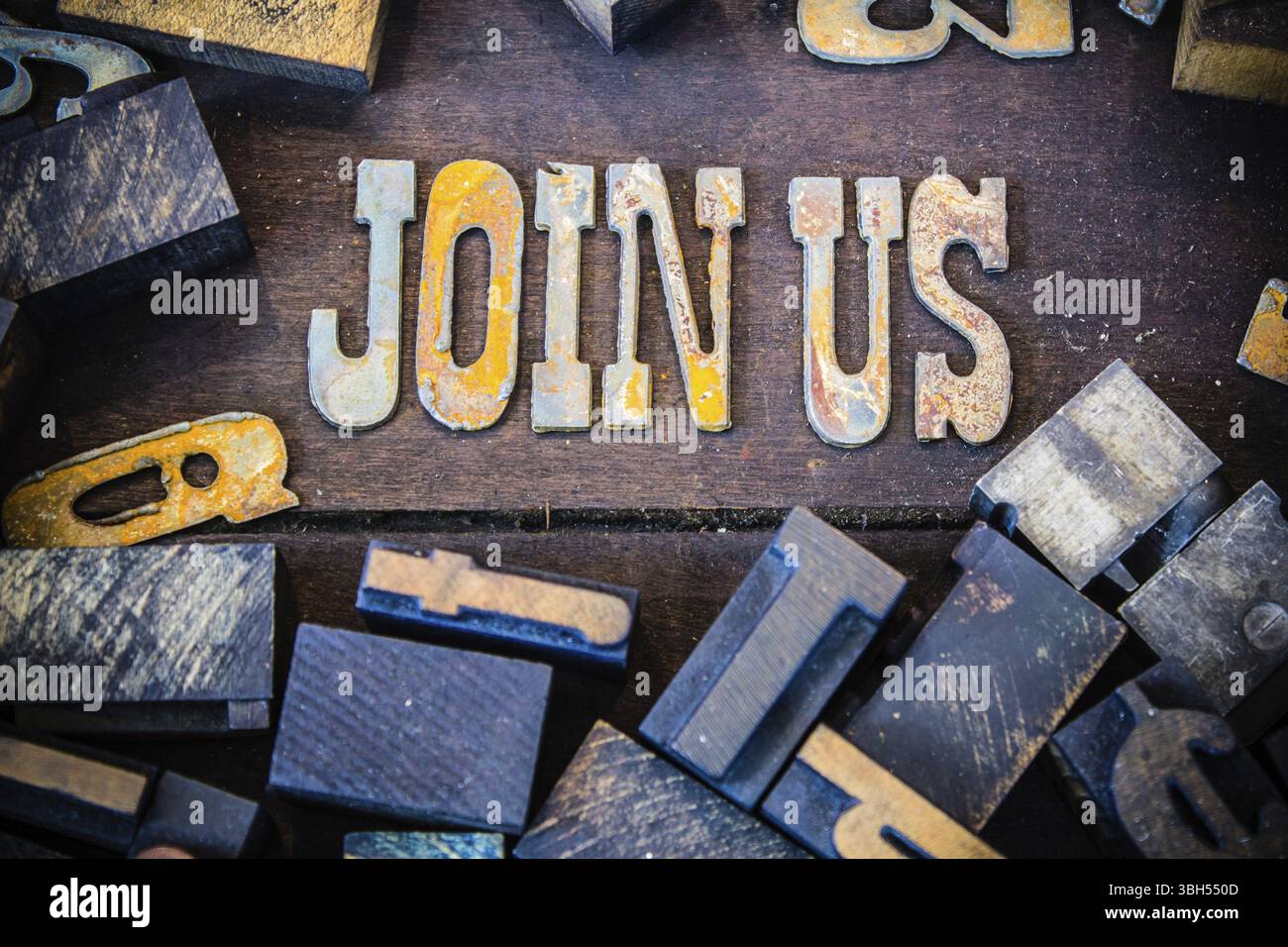 Le parole SI UNISCONO A noi scritte in lettere di metallo arrugginito circondate da caratteri vintage in legno e metallo Foto Stock