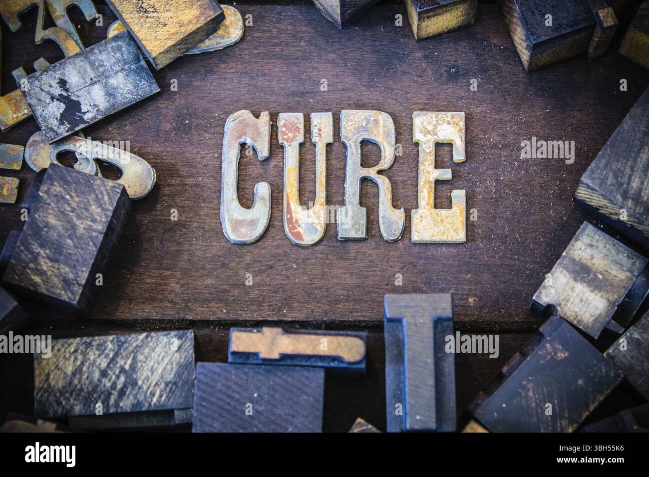 La parola CURE scritta in lettere di metallo arrugginito circondato da caratteri vintage in legno e metallo Foto Stock