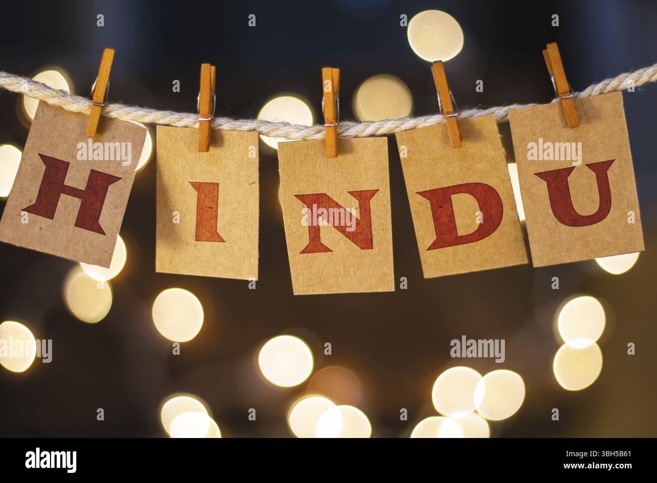 La parola INDÙ è stampata su carte clothespin tagliate davanti a luci incandescenti sfocate Foto Stock