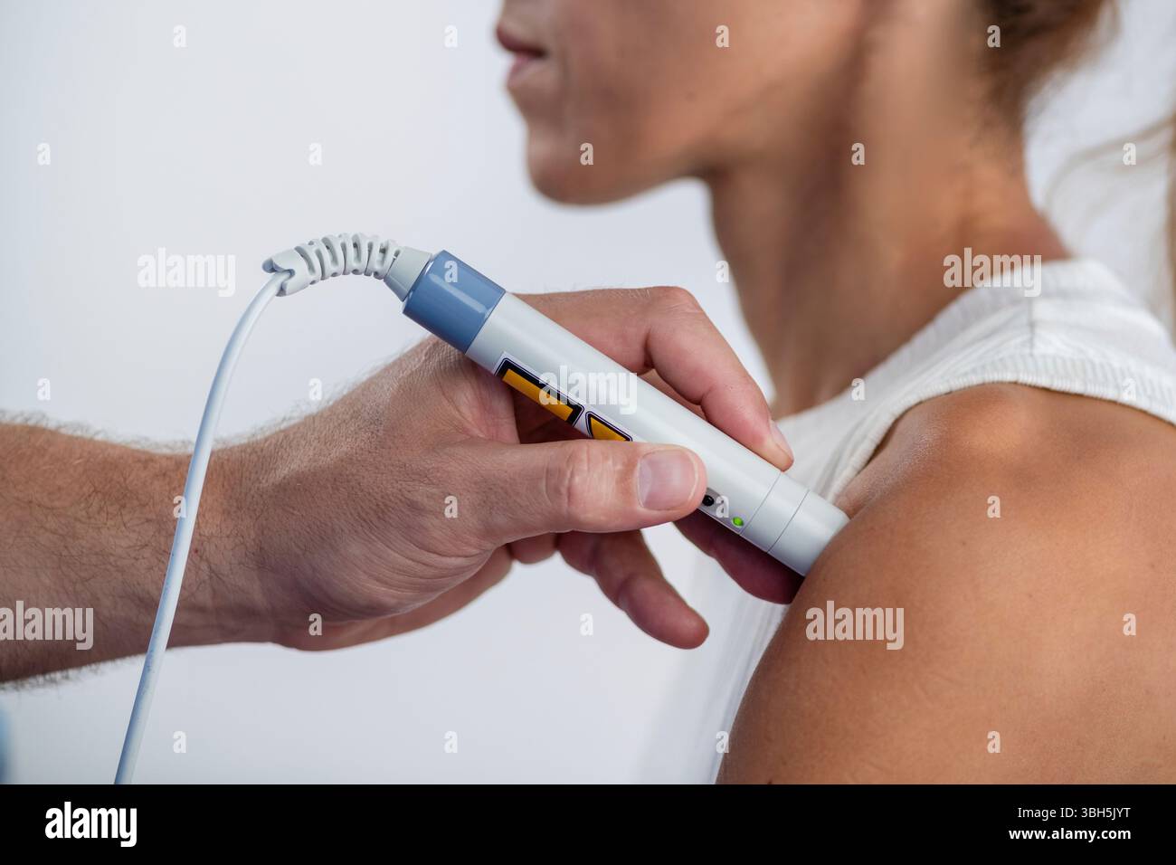 Il fisioterapista esegue la terapia laser sulla spalla del paziente per ridurre il dolore, ridurre l'infiammazione e promuovere la guarigione dei tessuti, favorendo un recupero più rapido e una maggiore mobilità. Foto Stock