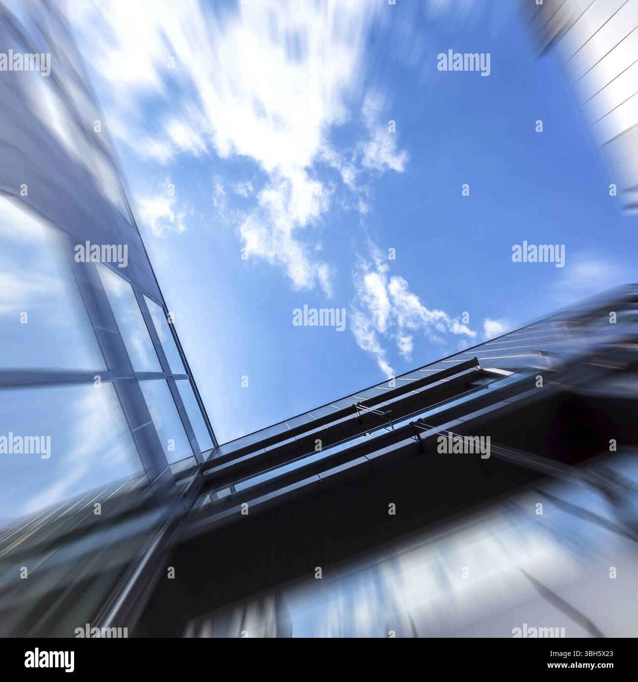 Vista dal basso del moderno edificio per uffici con effetto movimento che si muove verso il cielo. Concetto di stress, fuga, desiderio di libertà Foto Stock
