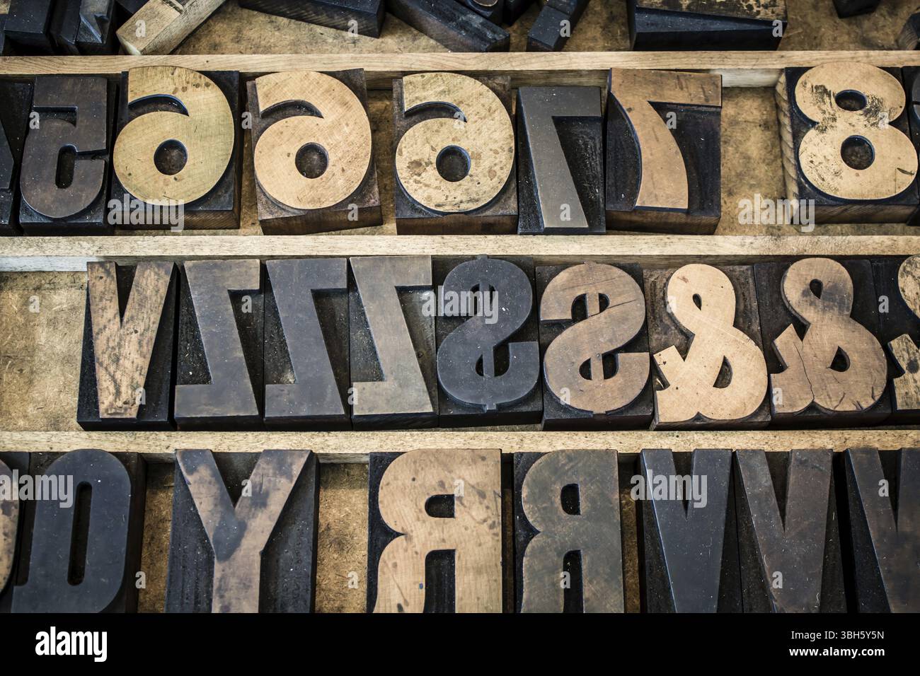 Un cassetto vintage di vecchie lettere, numeri e simboli in legno. Il tipo è macchiato di inchiostro e fotografato con le lettere naturalmente all'indietro come Foto Stock