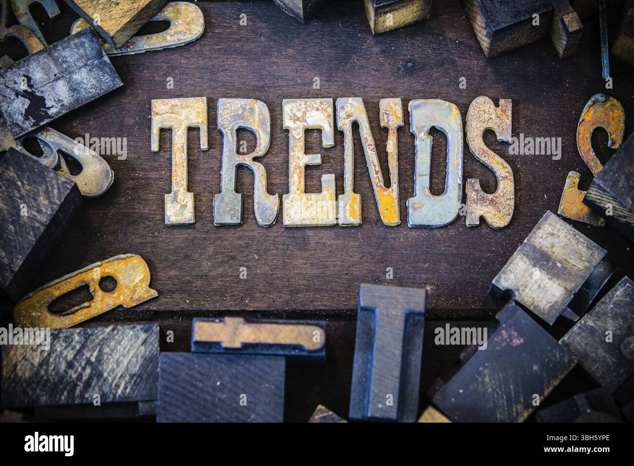 La parola TENDENZE scritta in lettere in metallo arrugginito circondato da caratteri vintage in legno e metallo Foto Stock