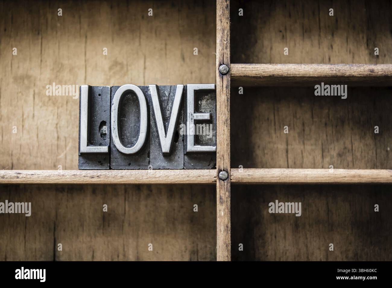 La parola "AMORE" scritta in stile vintage in metallo, seduta in un cassetto di legno Foto Stock