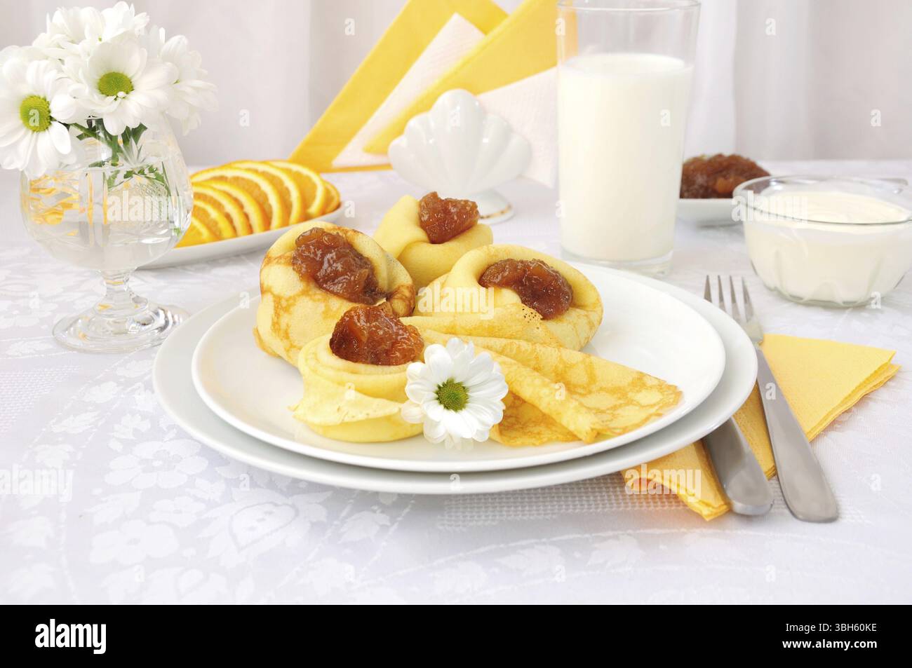 La prima colazione con pancake, confettura di albicocca e latte e arance Foto Stock