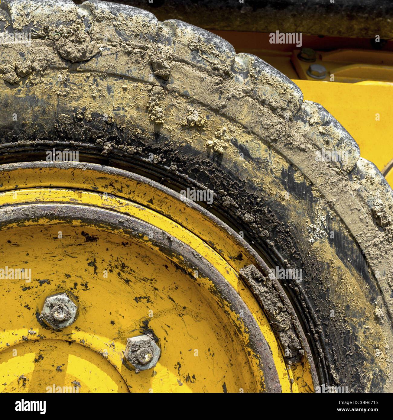 Primo piano estremo del bulldozer pneumatico, giallo e ricoperto di fango Foto Stock
