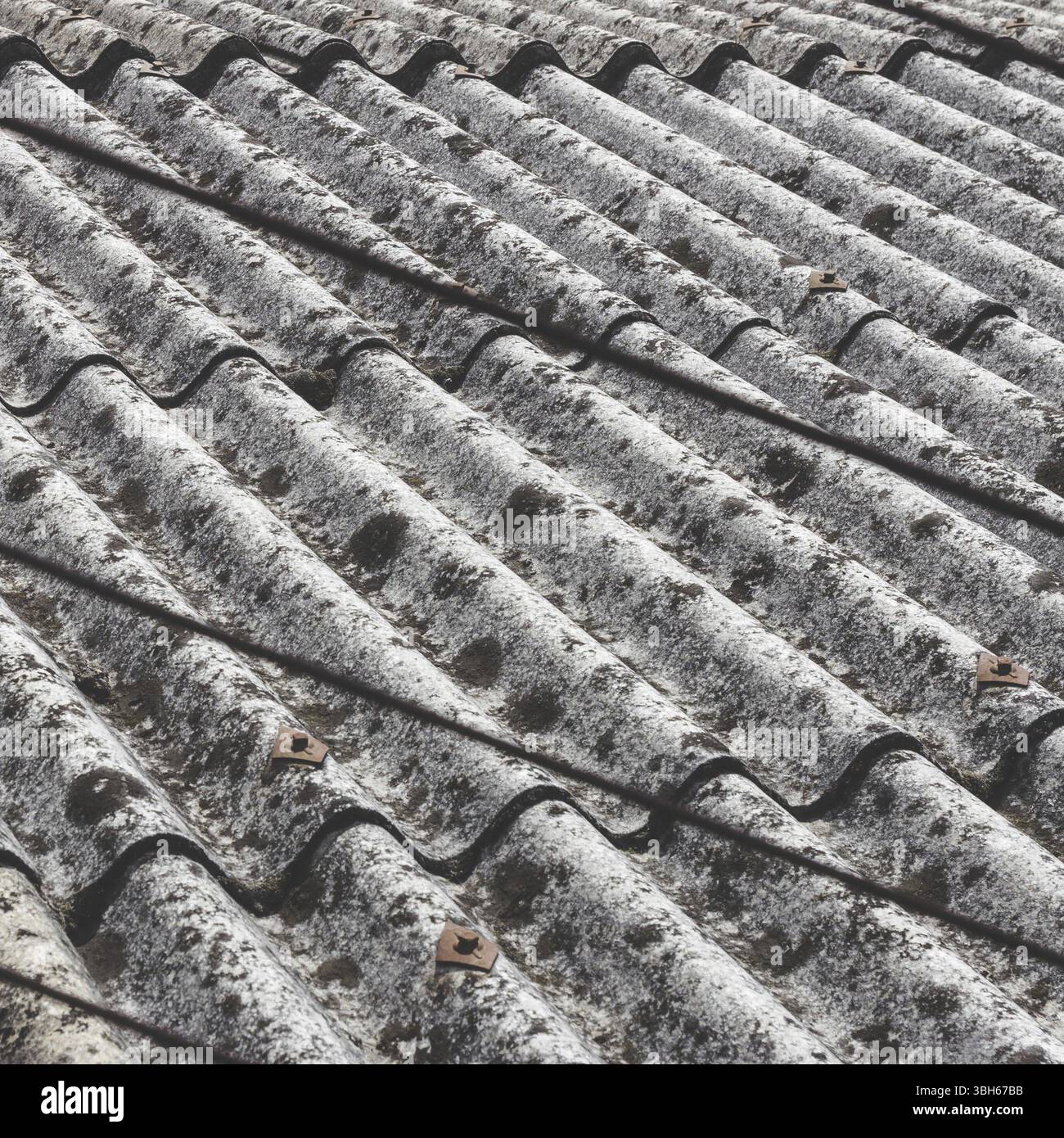 Tetto in amianto vecchio e pericoloso, uno dei materiali più pericolosi nel settore edile. Copertura del tetto Eternit di un vecchio e ammuffito Foto Stock