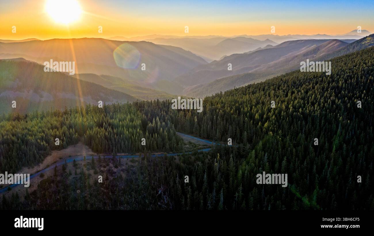 Wahtum Lake, Oregon - 14 agosto 2020: Una vista panoramica del tramonto sulle montagne e sulla foresta, con una strada che si snoda tra gli alberi. Foto Stock