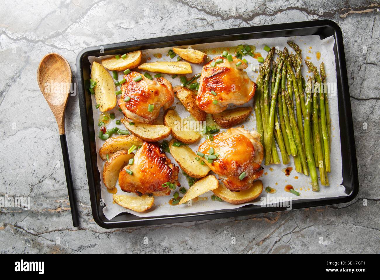 Spalmare il pollo in padella con asparagi e patate da vicino su un tavolo. Vista dall'alto orizzontale Foto Stock