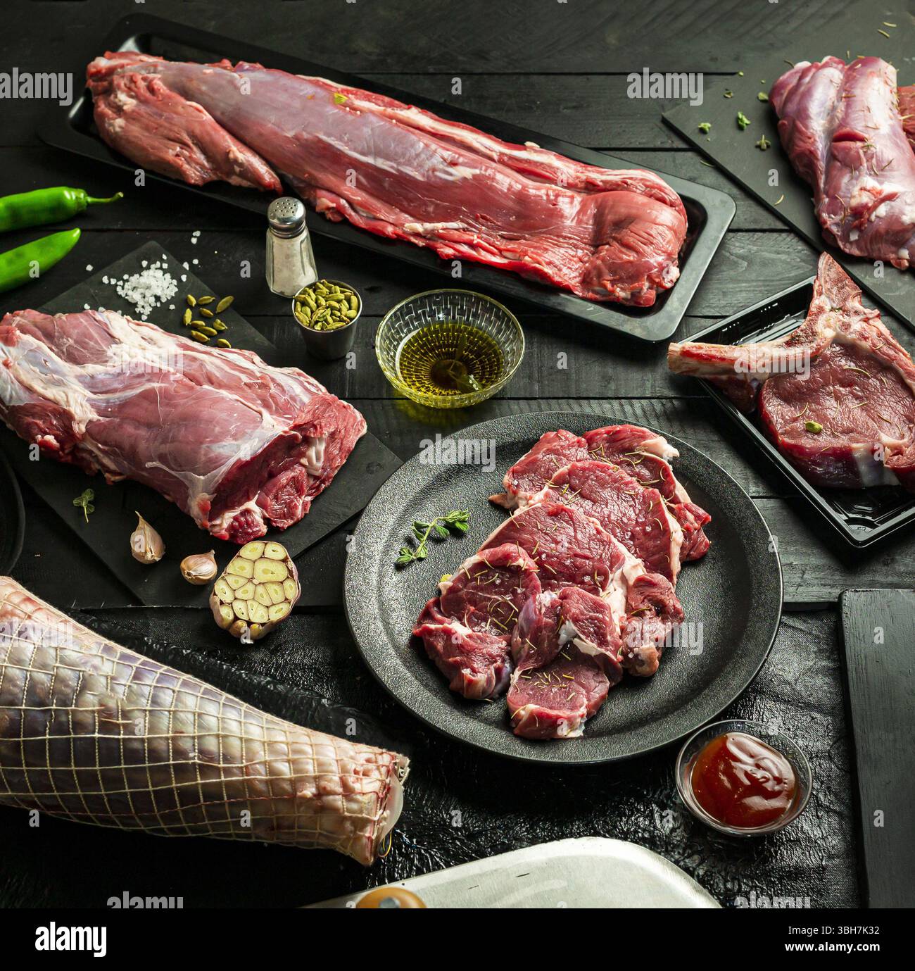 Tagli assortiti di vitello crudo da gamba, spalla, costola e pancia, sfondo nero. Foto Stock