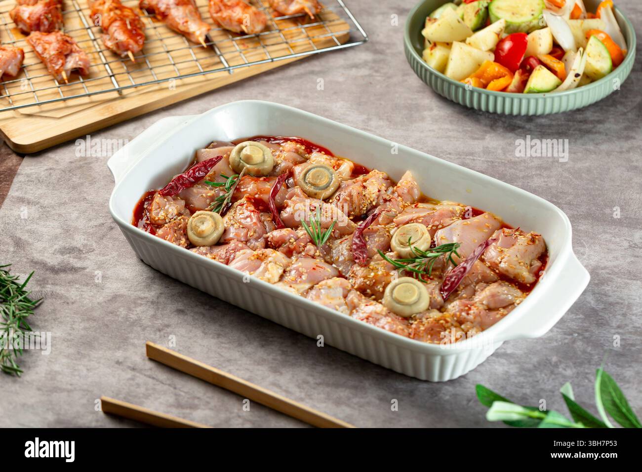 Piatto di pezzetti di pollo crudo con verdure pronte per il forno. 2 Foto Stock