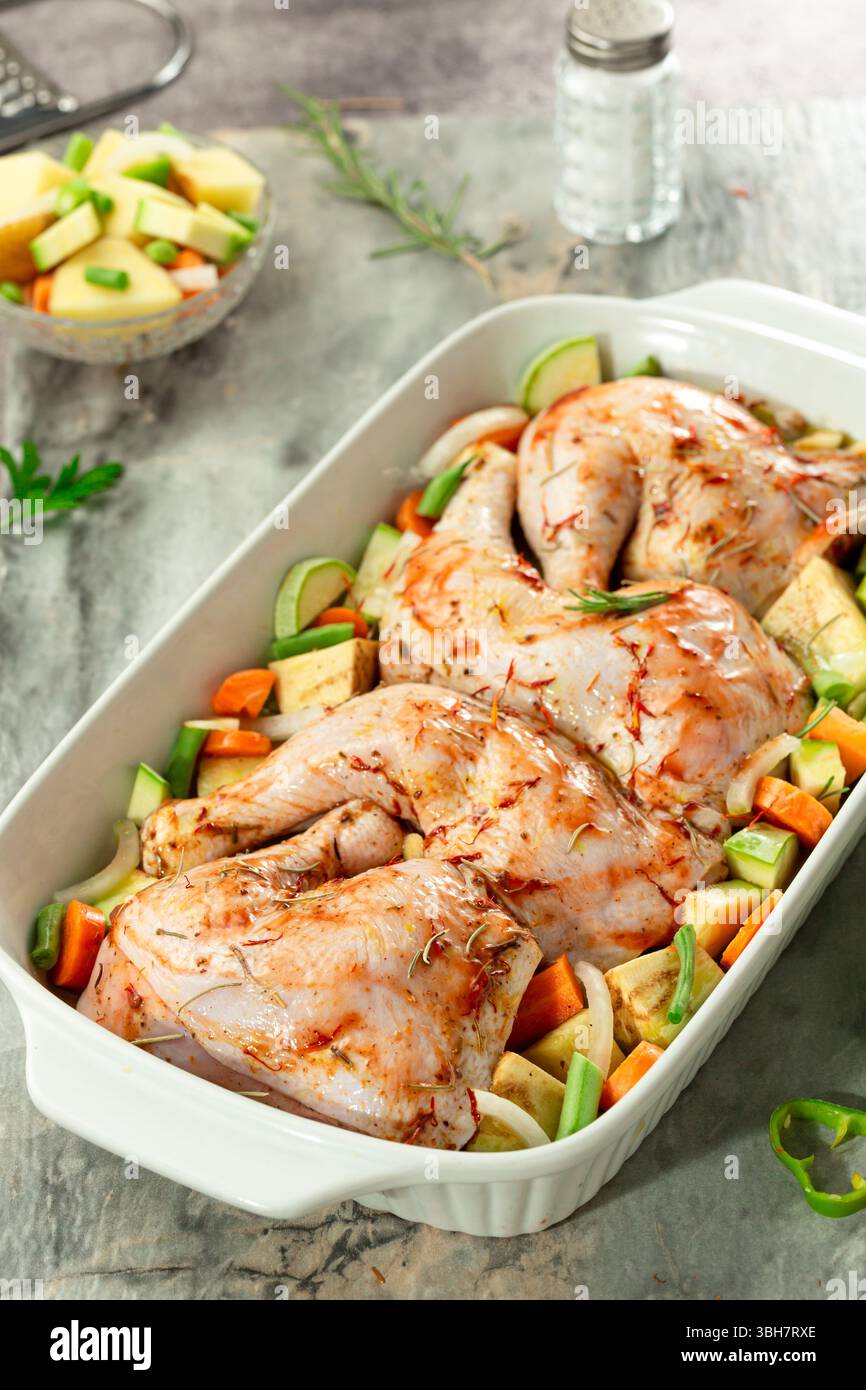 primo piano delle cosce del vassoio di pollo marinato crudo con verdure, Foto Stock