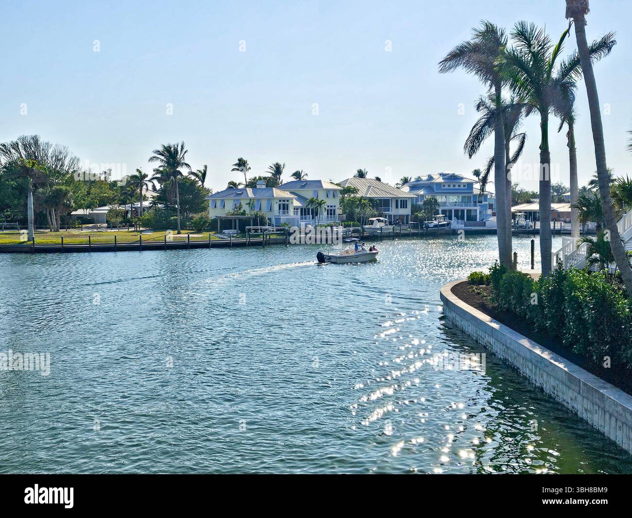 Area residenziale con canali a Boca grande, Gasparilla Island, Florida. Una piccola barca passa davanti a grandi case sul lungomare sui canali. Foto Stock