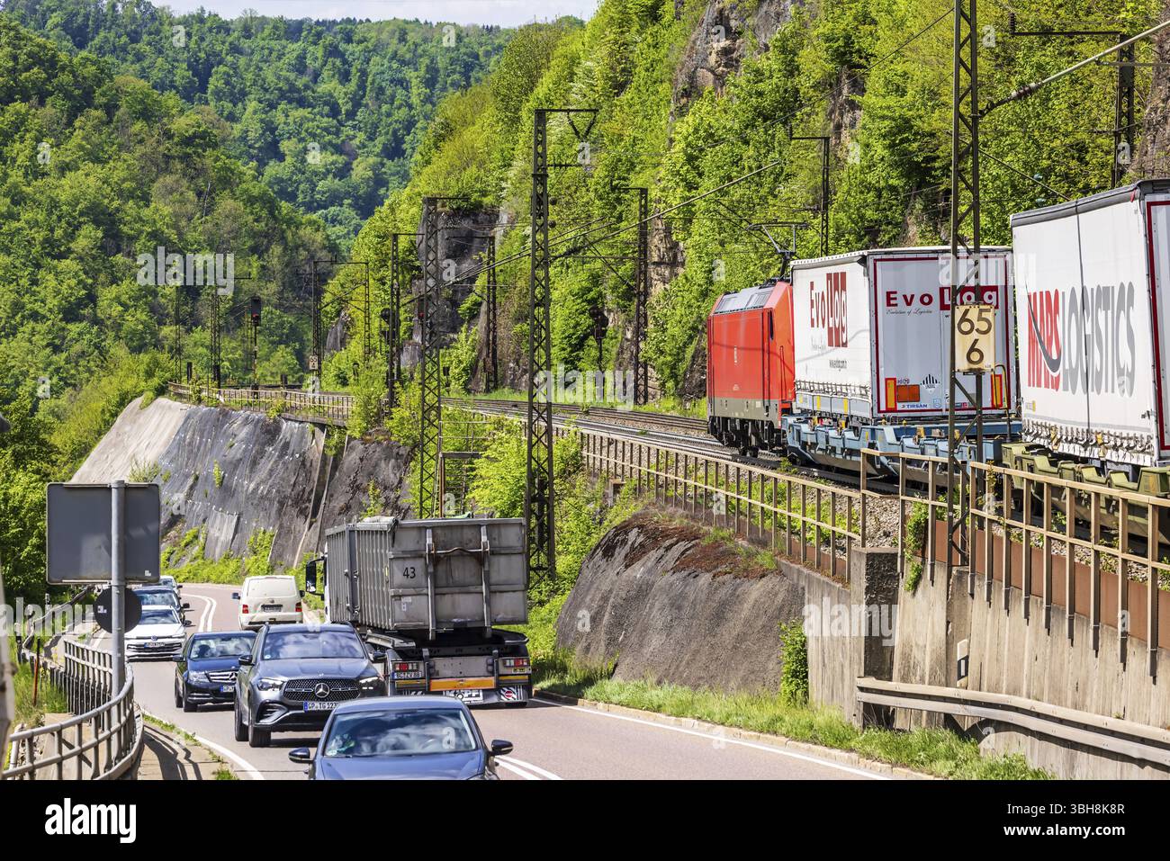 Treno merci sulla tortuosa linea ferroviaria della Geislinger Steige, accanto alla strada federale 10. Paesaggio lungo la linea ferroviaria Filstalline in primavera. Foto Stock